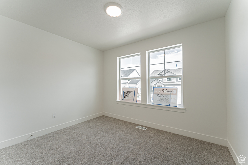 Carpeted spare room featuring baseboards