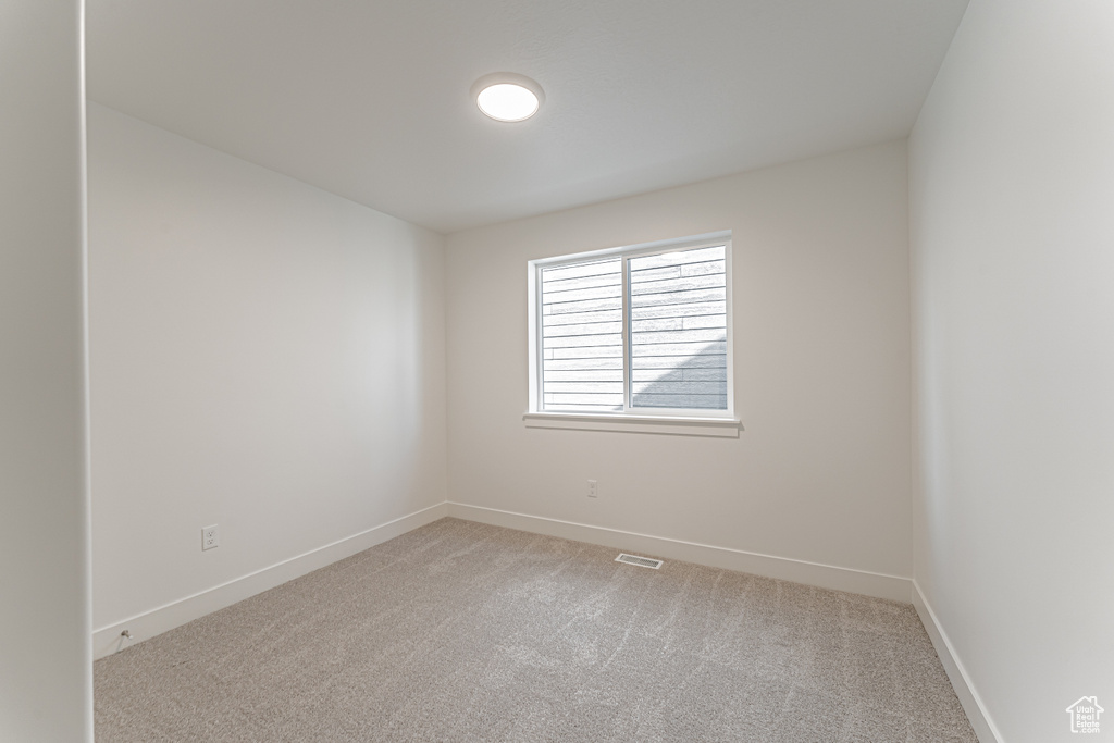 Empty room featuring light colored carpet and baseboards