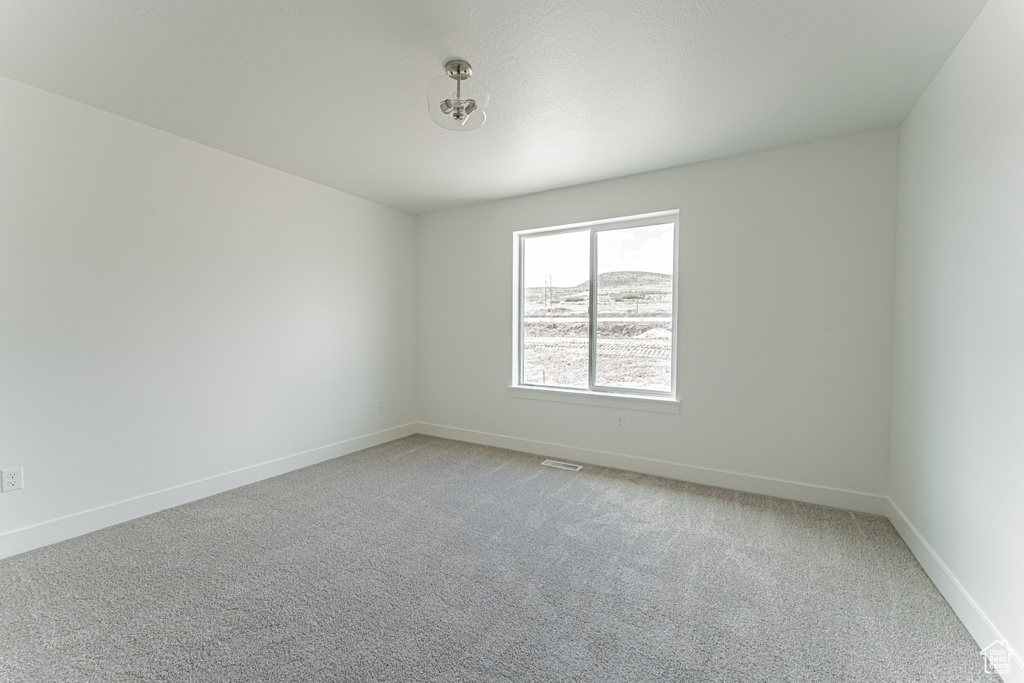 Spare room featuring light carpet and baseboards