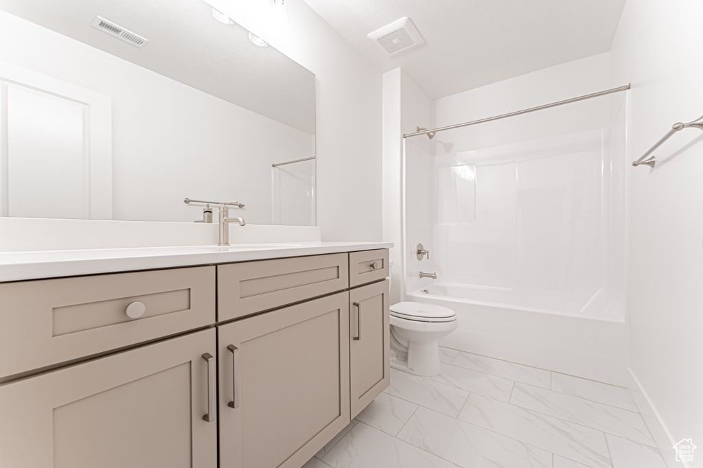 Full bath featuring vanity, marble look tile flooring, shower / washtub combination, toilet, and baseboards