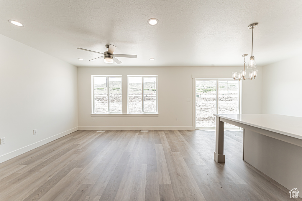 Spare room with a ceiling fan, light wood-type flooring, a chandelier, baseboards, and recessed lighting