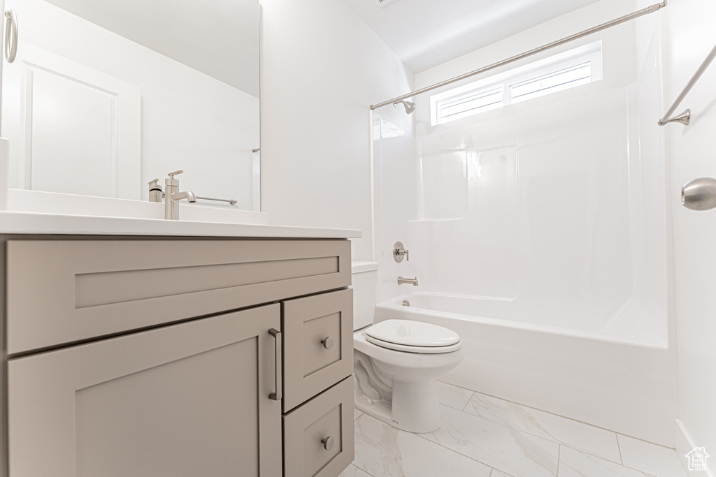 Bathroom with toilet, vanity, marble finish flooring, and shower / tub combination