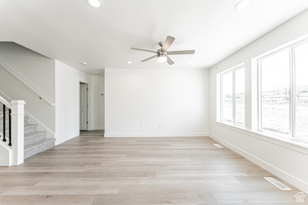 Unfurnished room with recessed lighting, a ceiling fan, stairway, light wood-type flooring, and baseboards