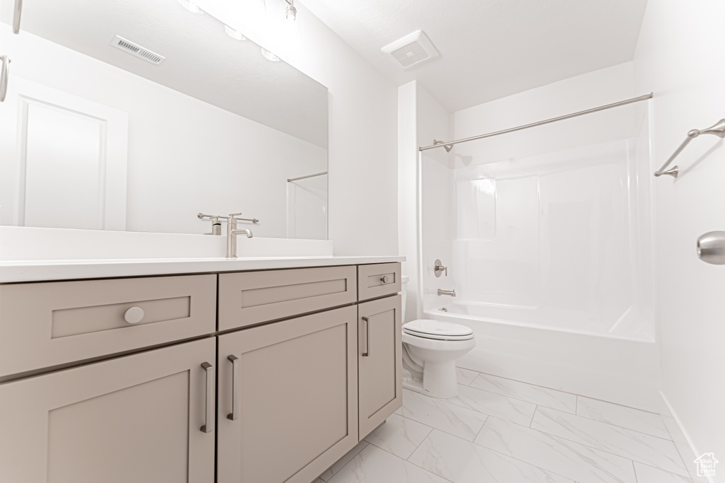 Full bath featuring marble finish floors, vanity, tub / shower combination, toilet, and baseboards