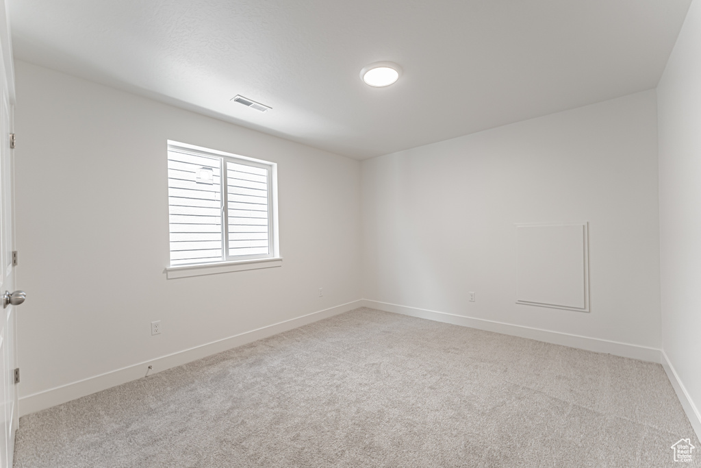 Spare room featuring carpet flooring and baseboards