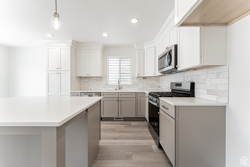 Kitchen with appliances with stainless steel finishes, recessed lighting, light countertops, a sink, and backsplash