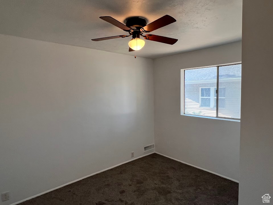 Carpeted empty room featuring ceiling fan and a textured ceiling