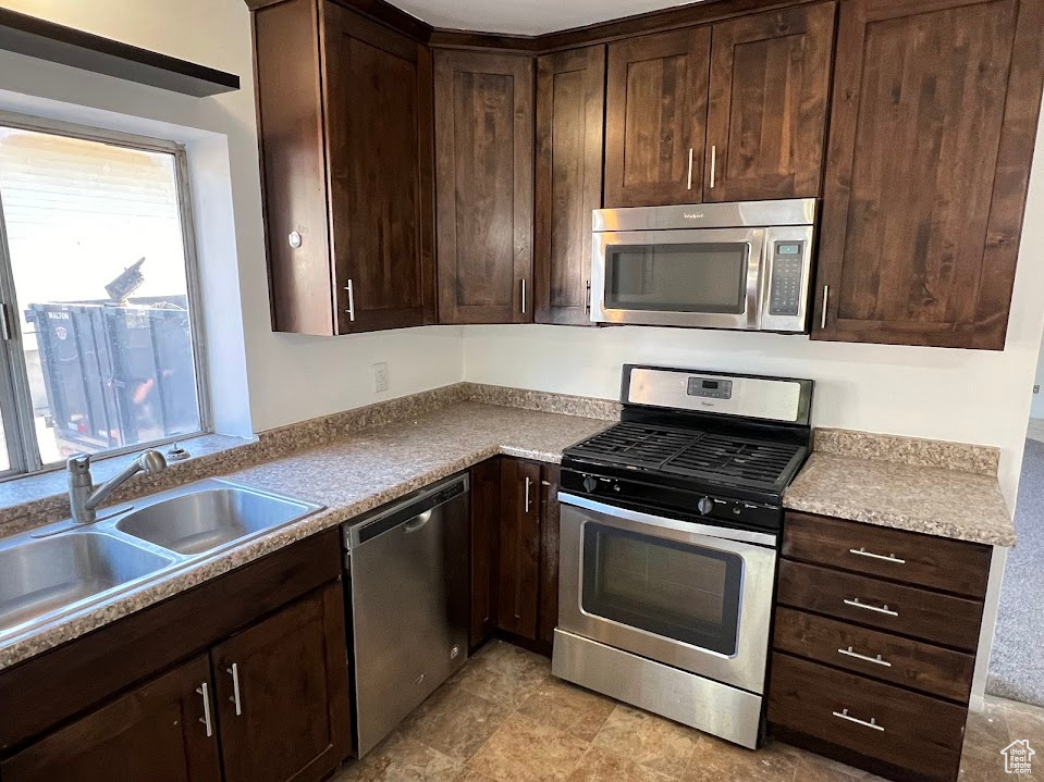 Kitchen with a healthy amount of sunlight, appliances with stainless steel finishes, and dark brown cabinets