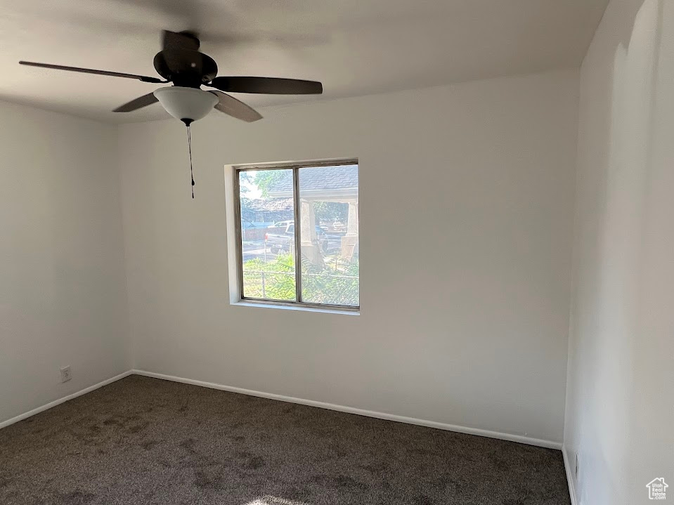 Carpeted spare room featuring ceiling fan