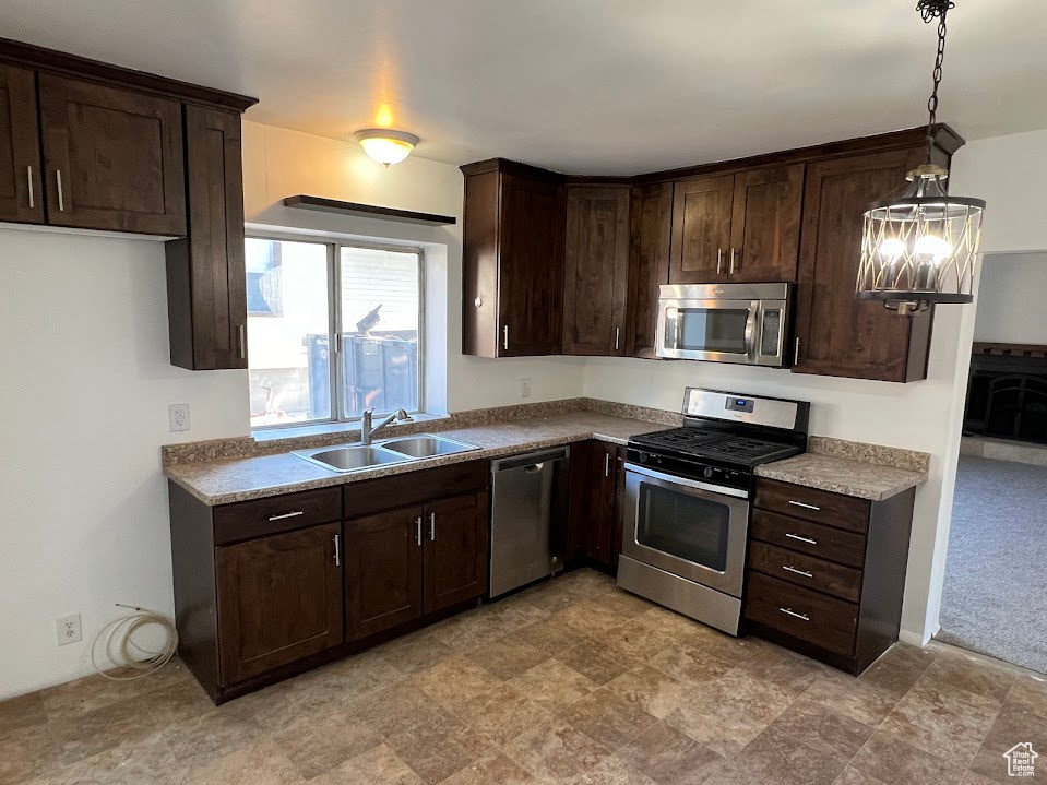 Kitchen featuring stainless steel appliances, sink, decorative light fixtures, and dark brown cabinets