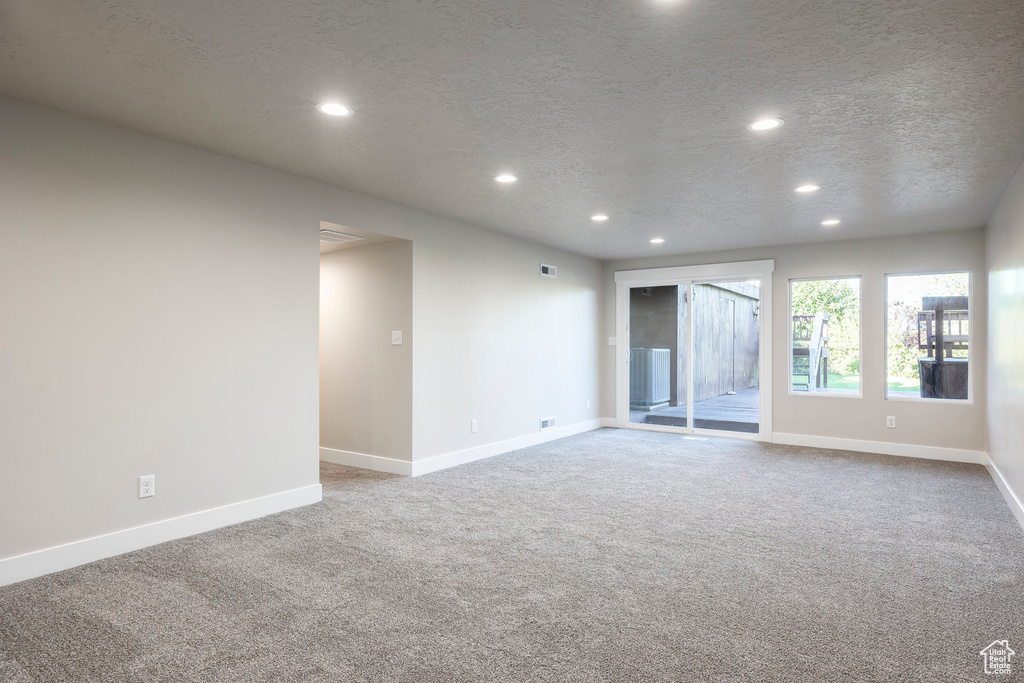 Unfurnished room featuring a textured ceiling and light colored carpet