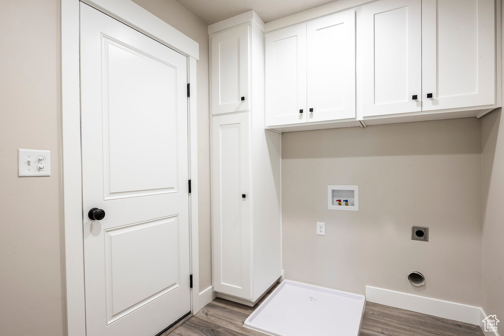 Laundry area with hookup for a washing machine, cabinets, hardwood / wood-style floors, and hookup for an electric dryer