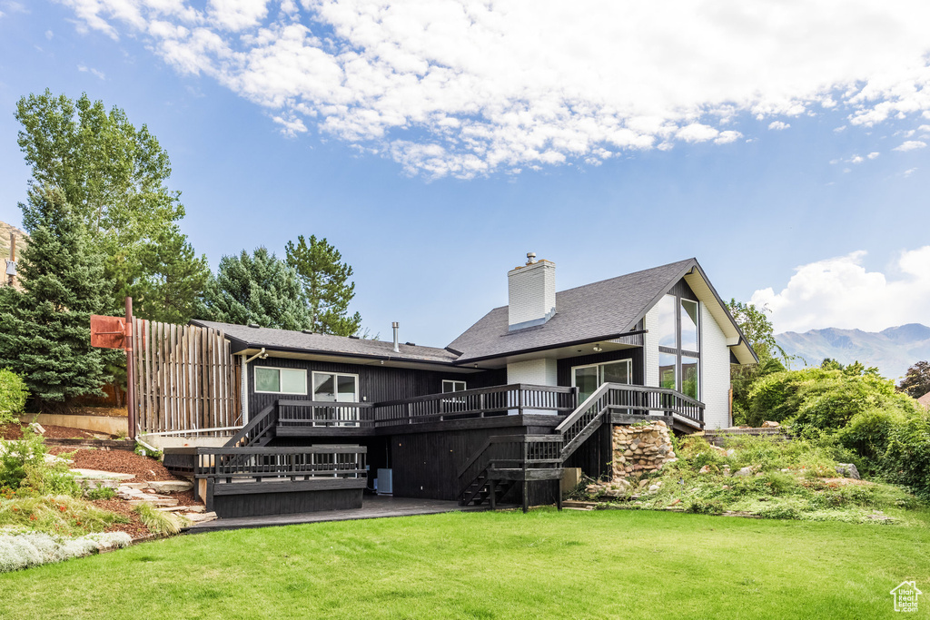 Back of house featuring a yard and a deck with mountain view