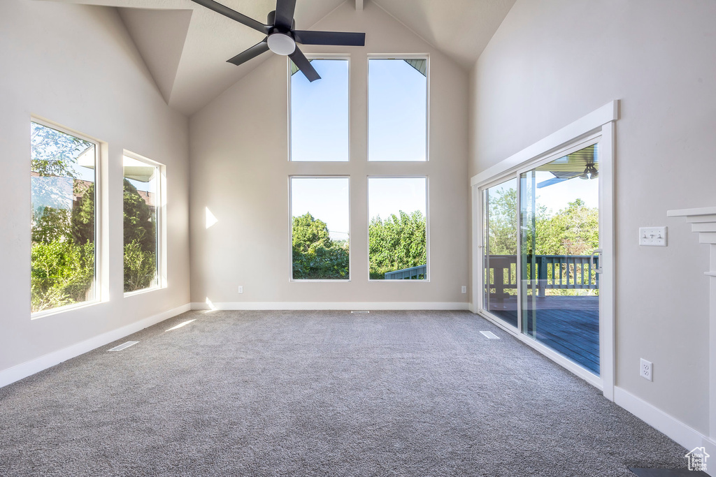 Carpeted empty room with high vaulted ceiling and ceiling fan