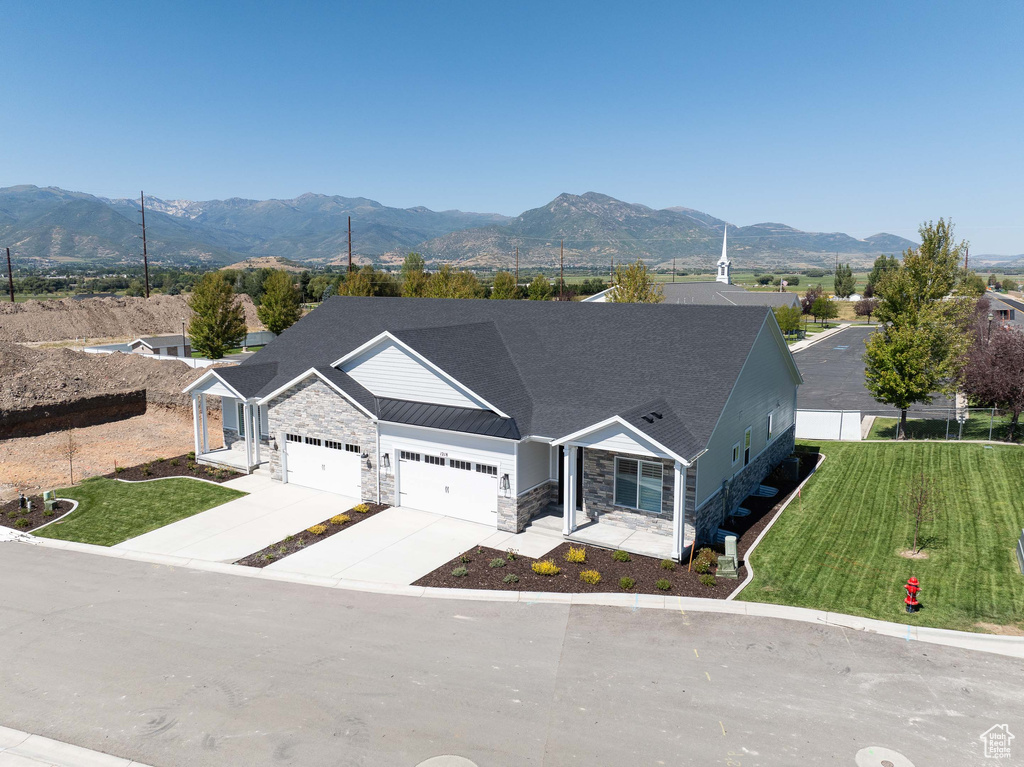 View of front facade featuring a front lawn, a garage, and a mountain view