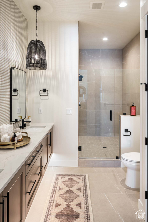 Bathroom featuring an enclosed shower, tile patterned floors, toilet, and vanity