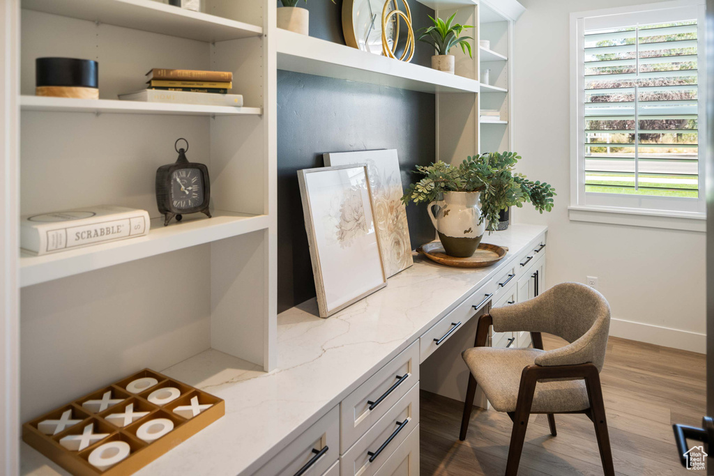 Office space featuring light wood-type flooring, built in desk, and plenty of natural light