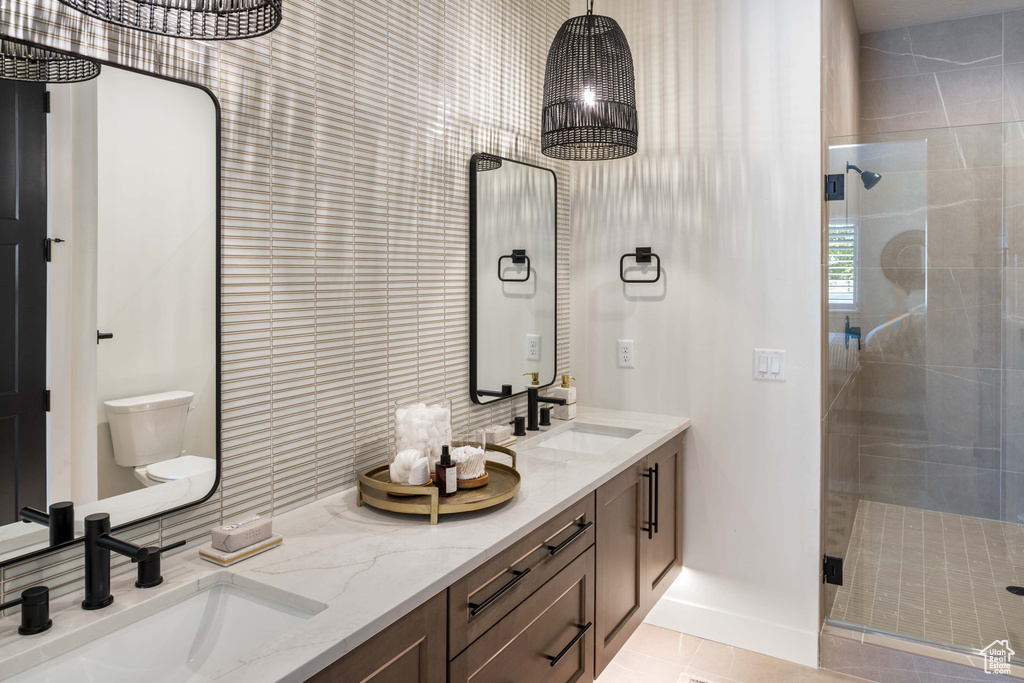 Bathroom with vanity, toilet, an enclosed shower, and tile patterned floors