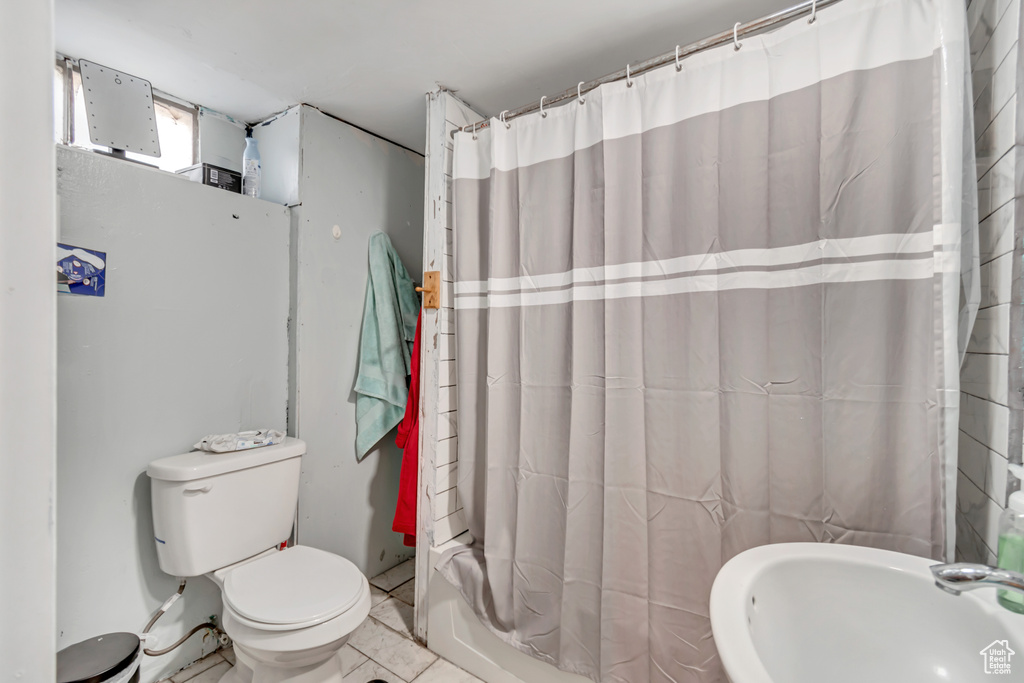 Bathroom with toilet, sink, and tile patterned flooring
