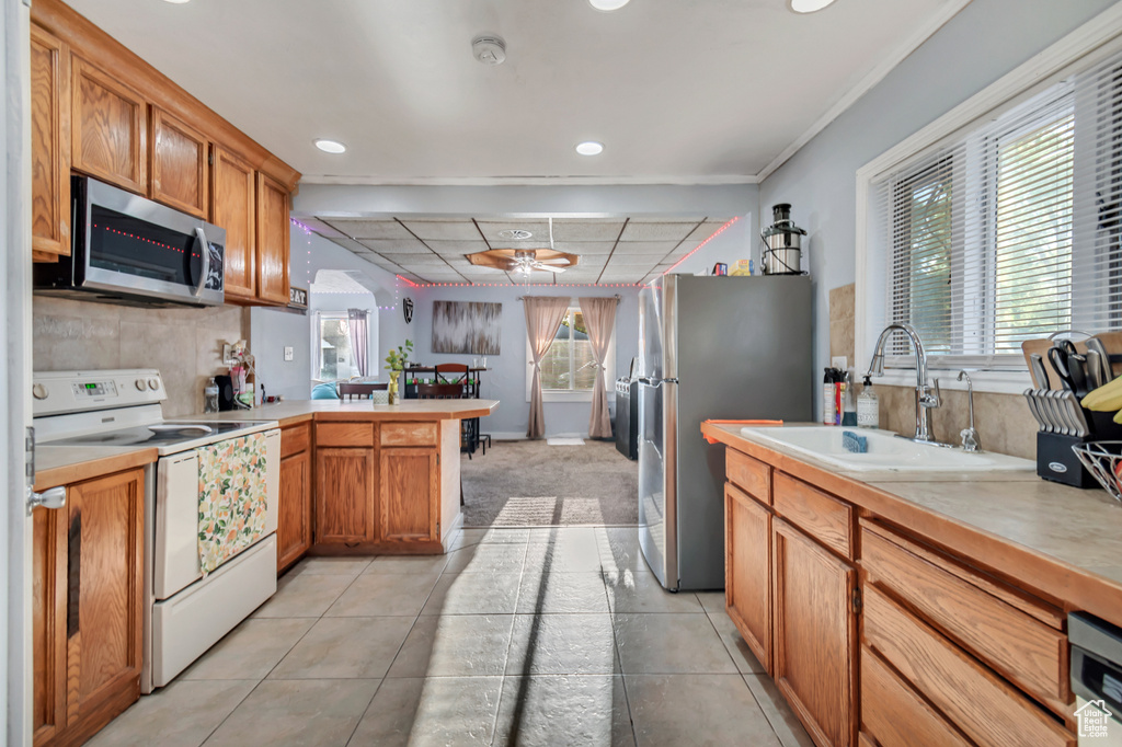 Kitchen with light tile patterned floors, stainless steel appliances, sink, kitchen peninsula, and ceiling fan