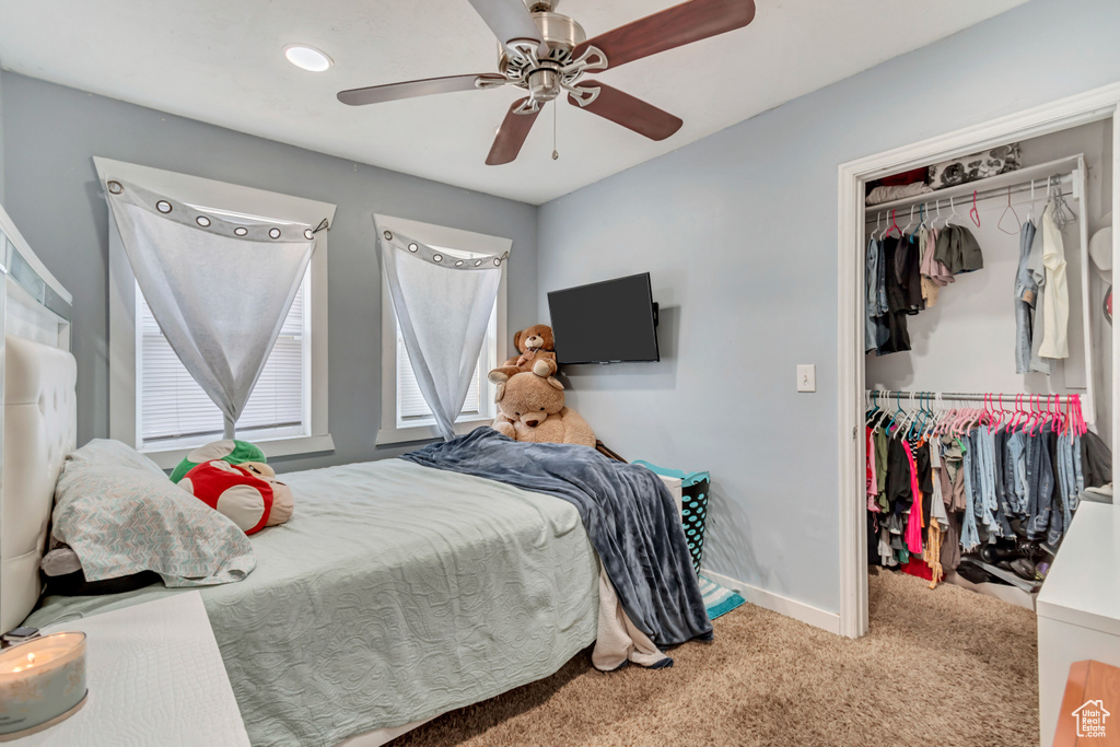 Carpeted bedroom with ceiling fan and a closet