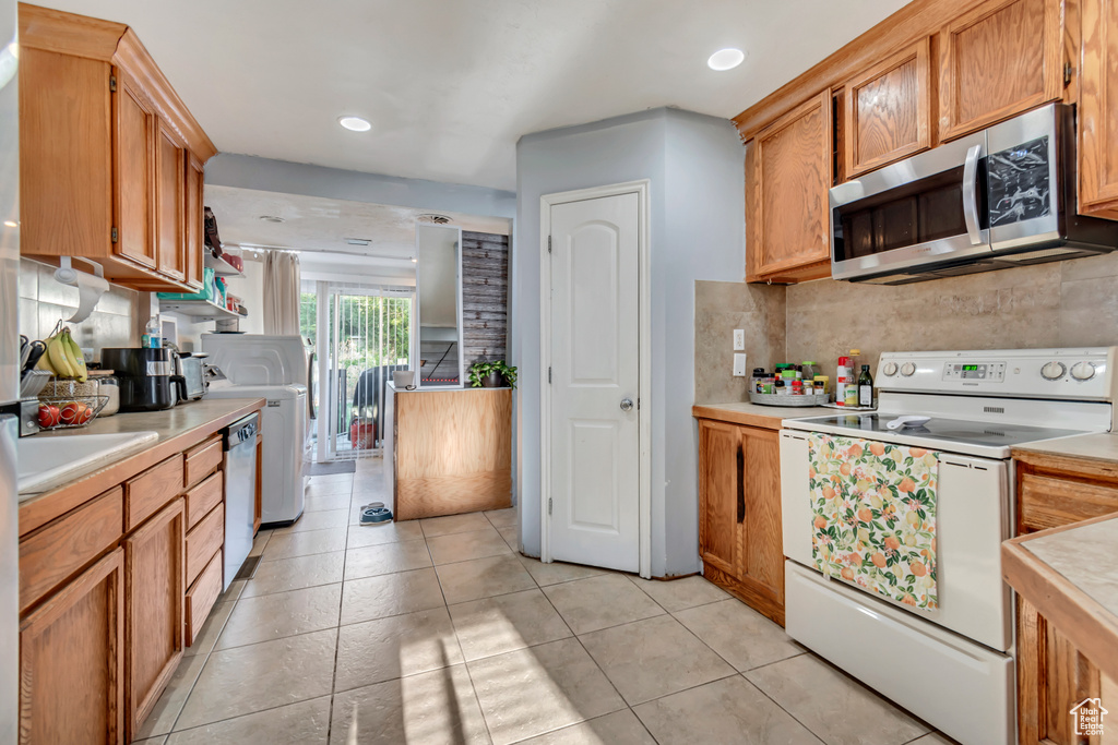 Kitchen featuring sink, backsplash, stainless steel appliances, and light tile patterned flooring
