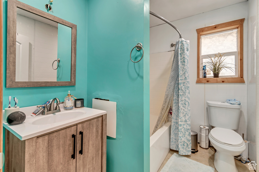 Full bathroom featuring tile patterned floors, shower / bathtub combination with curtain, toilet, and vanity
