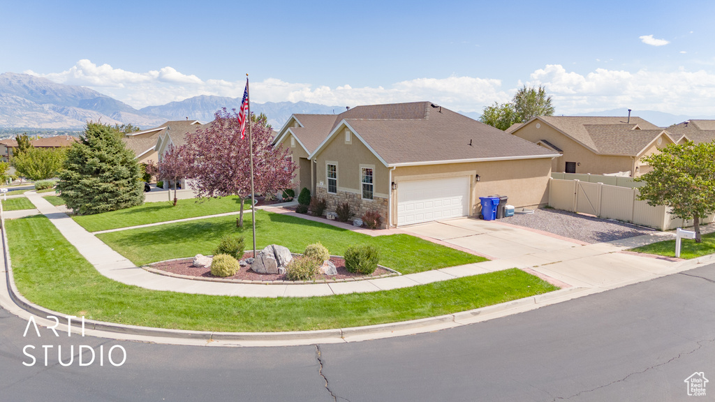 Ranch-style home with a mountain view, a garage, and a front lawn