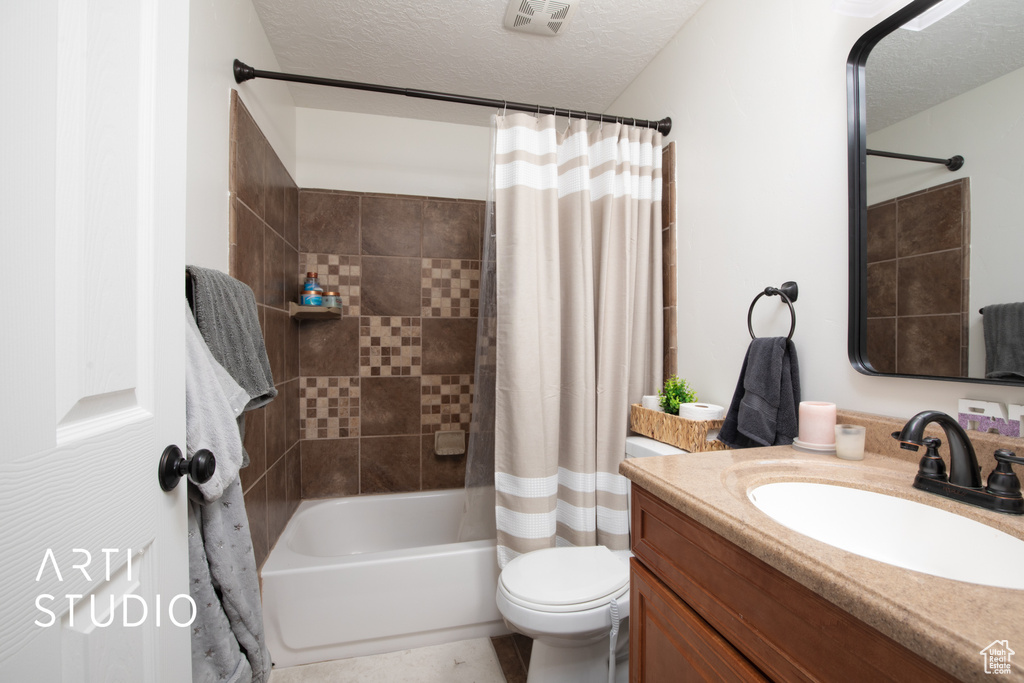 Full bathroom with shower / bath combination with curtain, toilet, a textured ceiling, and vanity