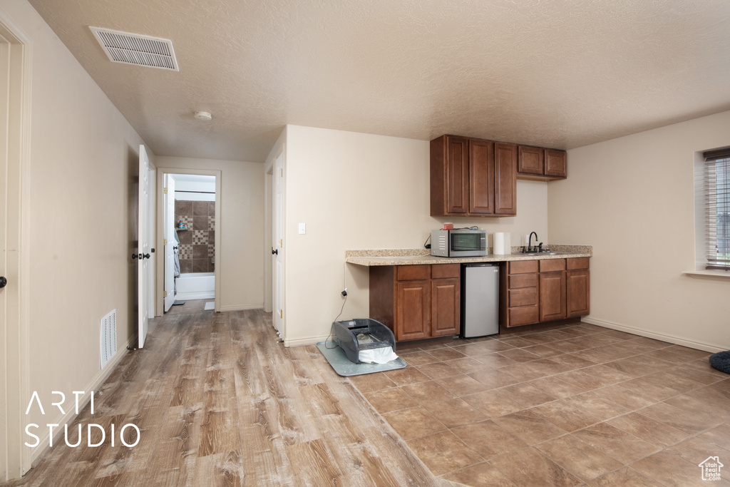 Kitchen with a textured ceiling and light hardwood / wood-style floors