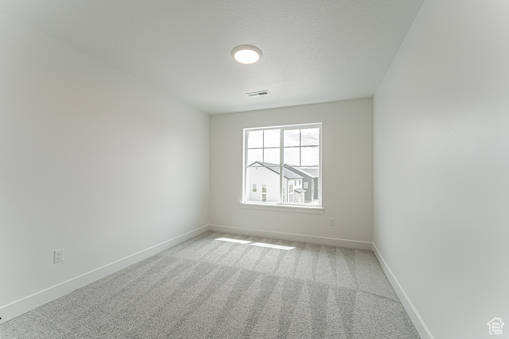 Carpeted empty room featuring baseboards and a textured ceiling