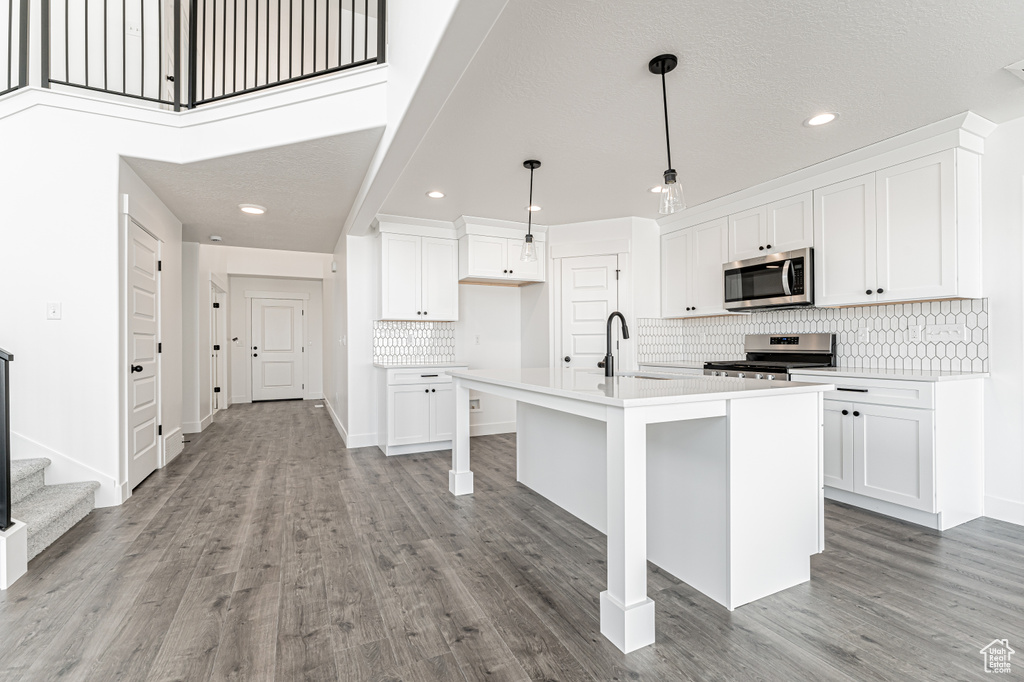 Kitchen featuring appliances with stainless steel finishes, a sink, tasteful backsplash, light countertops, and recessed lighting