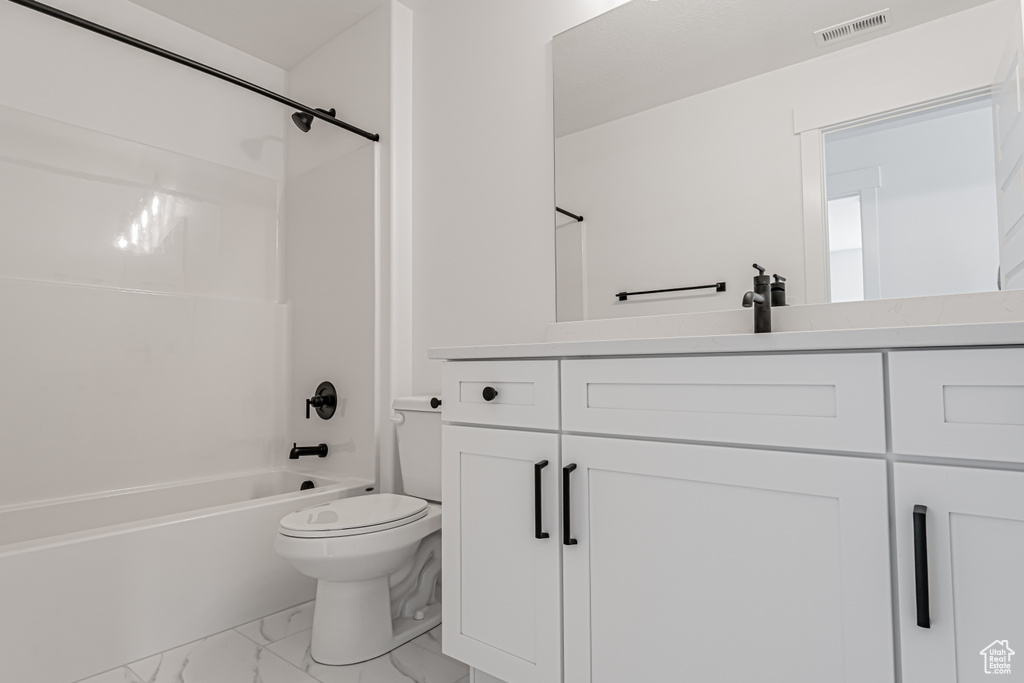 Full bathroom with marble look tiles, toilet, vanity, and shower / bath combination
