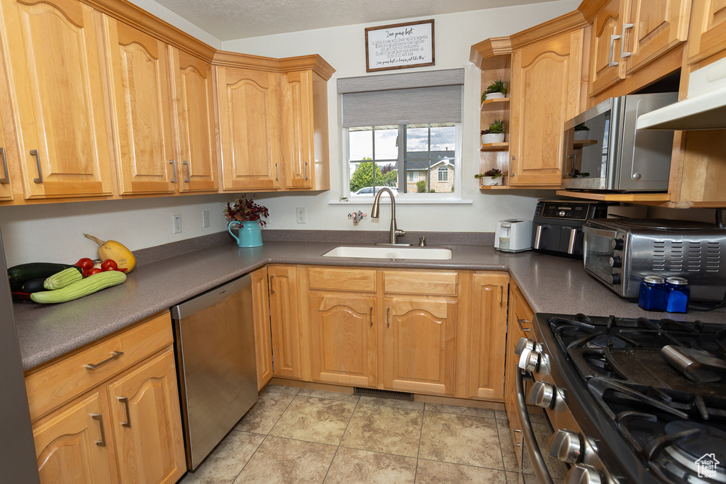 Kitchen featuring appliances with stainless steel finishes, a textured ceiling, light tile patterned flooring, and sink