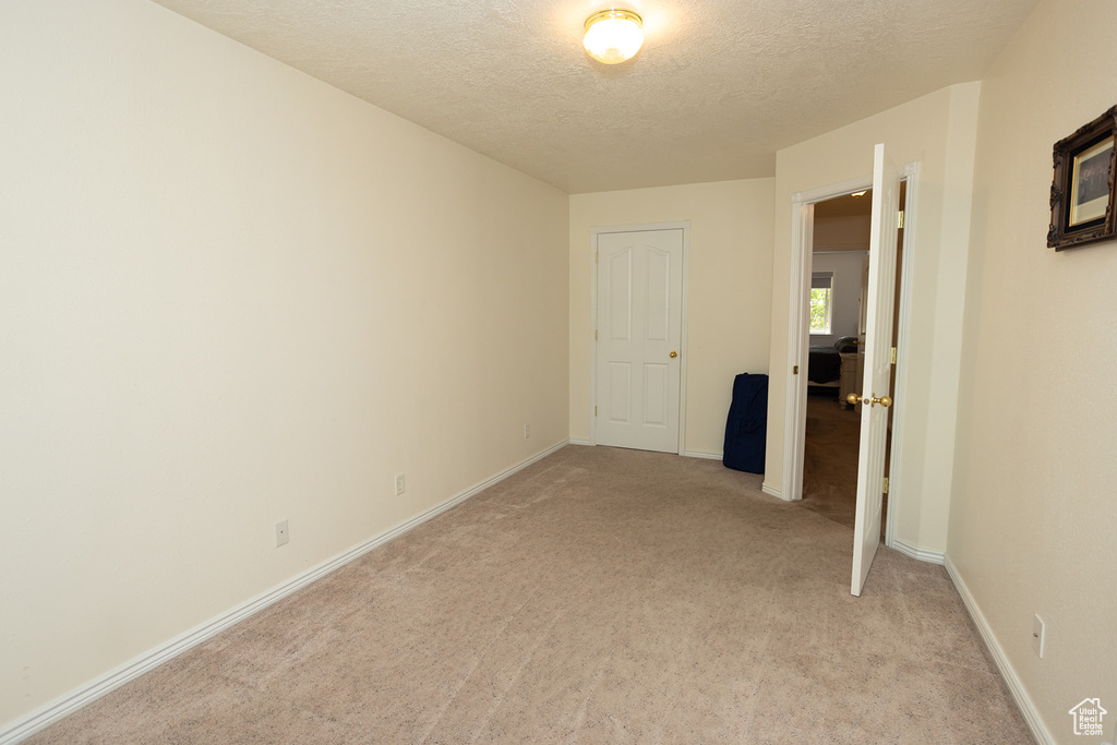 Unfurnished room with light carpet and a textured ceiling