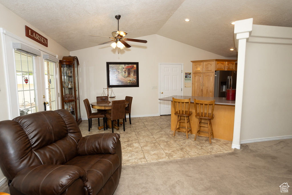 Living room featuring light carpet, lofted ceiling, ceiling fan, and a textured ceiling