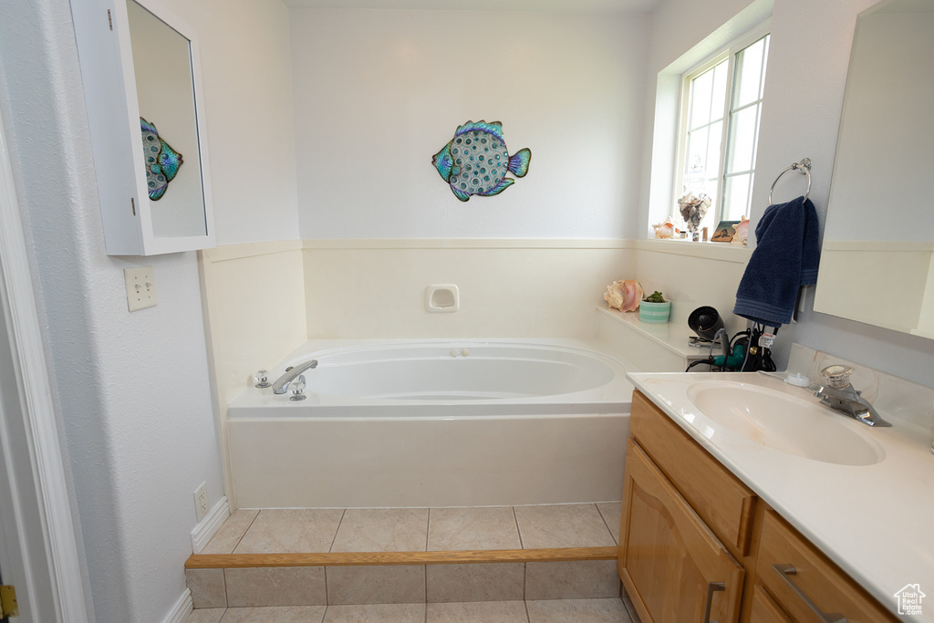 Bathroom with vanity, a bathing tub, and tile patterned flooring