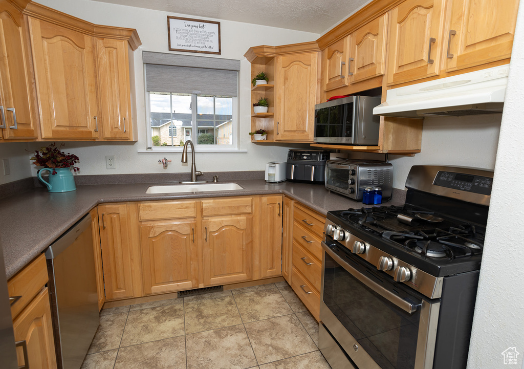 Kitchen featuring a textured ceiling, sink, light tile patterned floors, and appliances with stainless steel finishes