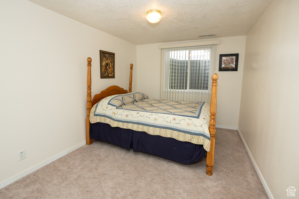 Bedroom featuring light colored carpet and a textured ceiling