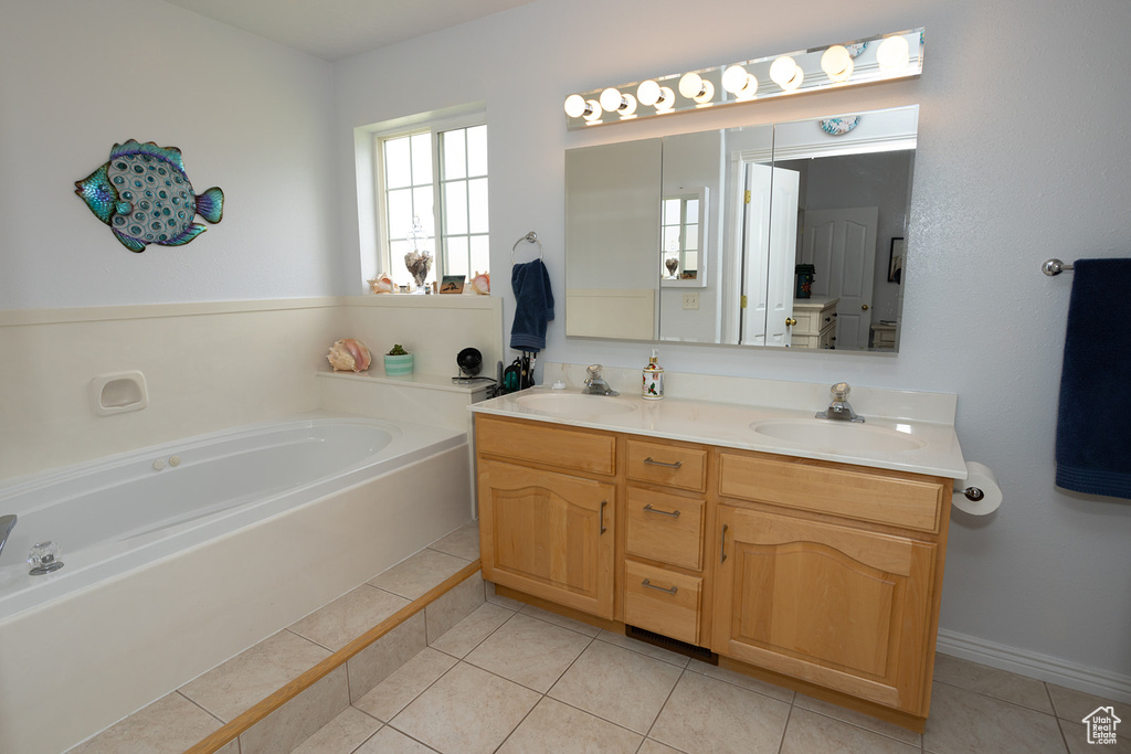 Bathroom with a tub to relax in, vanity, and tile patterned flooring