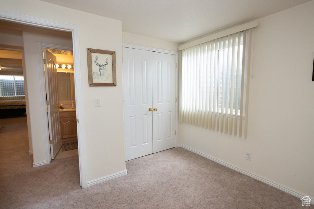 Unfurnished bedroom featuring light colored carpet, a closet, and multiple windows