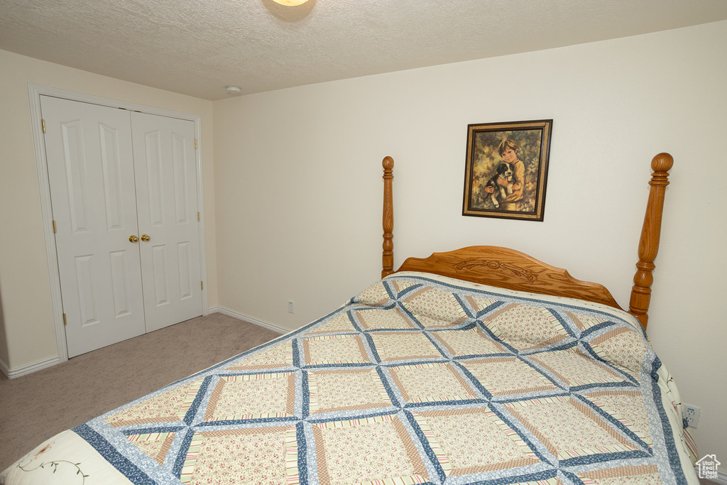 Carpeted bedroom featuring a textured ceiling and a closet