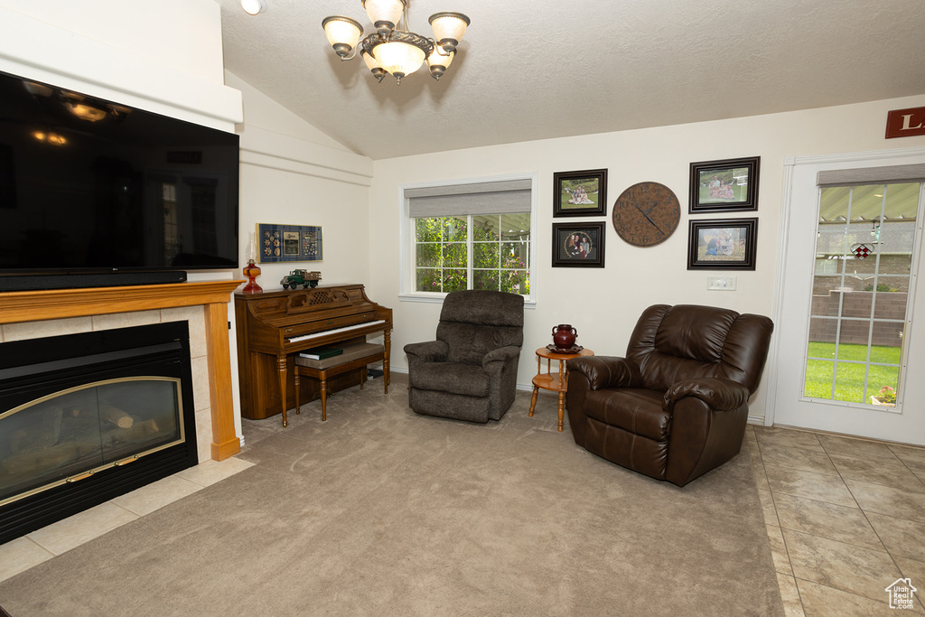 Living room featuring a textured ceiling, vaulted ceiling, an inviting chandelier, a fireplace, and light colored carpet