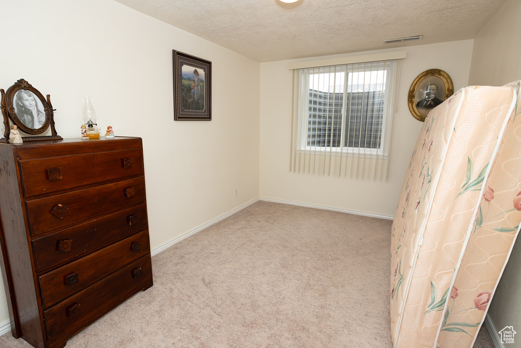 Bedroom featuring a textured ceiling and light colored carpet