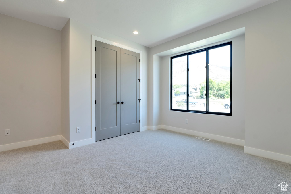 Empty room with light colored carpet and a healthy amount of sunlight