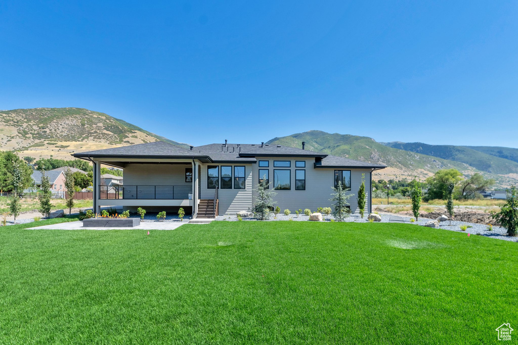 Rear view of house with a lawn, a patio, and a mountain view