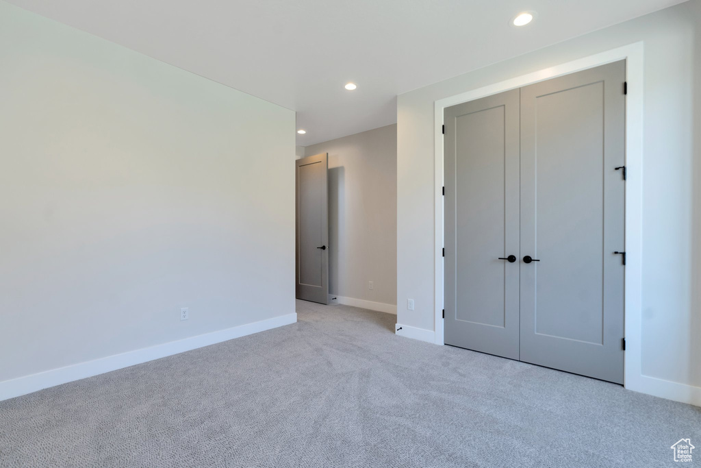 Unfurnished bedroom featuring light colored carpet and a closet