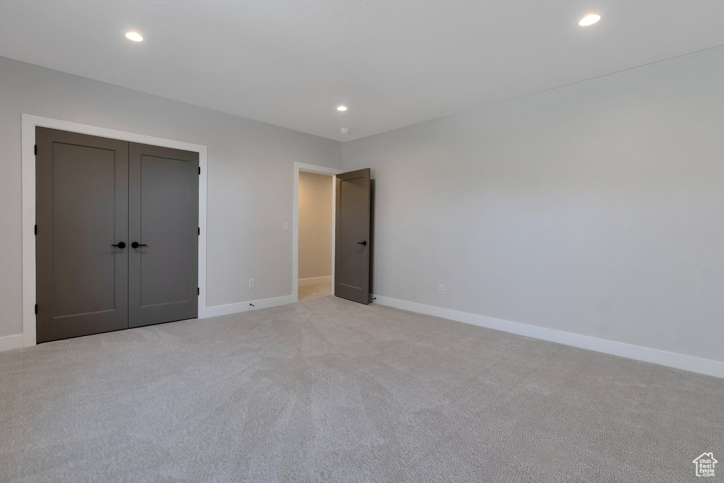 Unfurnished bedroom with a closet and light carpet