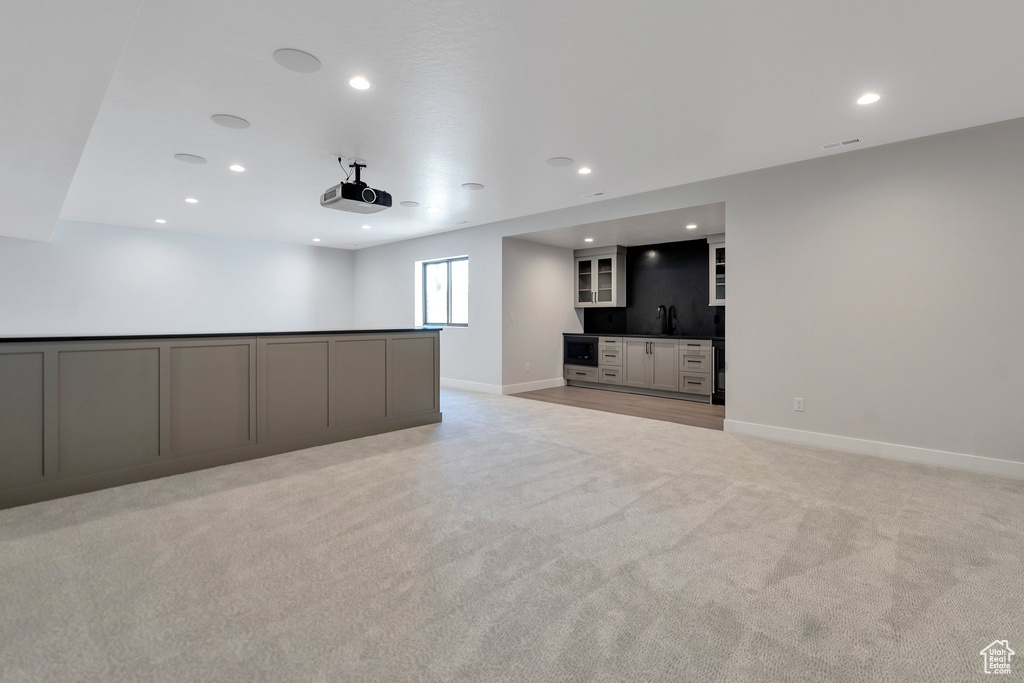 Unfurnished living room featuring light carpet and wet bar