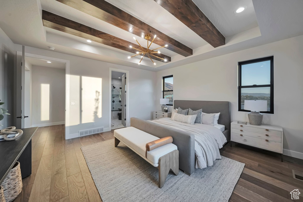 Bedroom with ensuite bathroom, multiple windows, an inviting chandelier, and dark hardwood / wood-style flooring